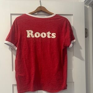 Roots Red tee with white . Roots on back . Maple leaf on front